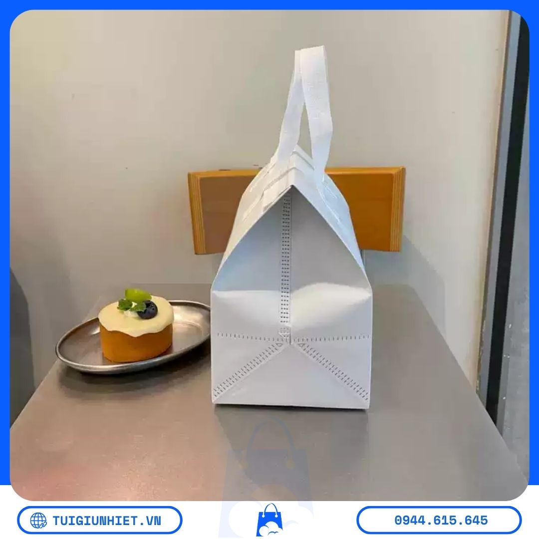 Túi Vải Không Dệt Đựng Bánh Giữ Nhiệt: Giải Pháp Bao Bì Kinh Tế Và Hiệu Quả Cho Tiệm Bánh Túi vải không dệt đựng bánh giữ nhiệt màu trắng, thiết kế có quai xách, phù hợp vận chuyển bánh ngọt và thực phẩm.