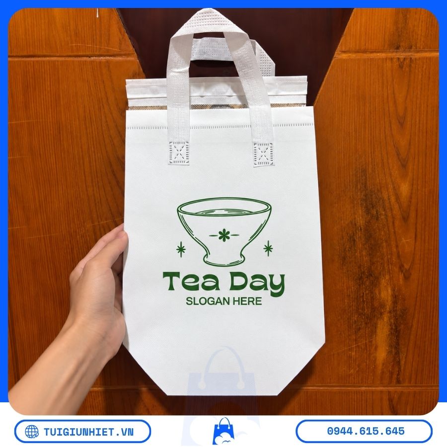 Túi giao đồ ăn in logo cho quán trà sữa – Nên chọn loại nào? Túi Giao Đồ Ăn In Logo Tea Day màu trắng, có quai xách chắc chắn và in logo thương hiệu, phù hợp sử dụng cho quán trà và đồ uống.